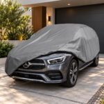 Siva univerzalna cerada djelimično postavljena preko automobila ispred garaže